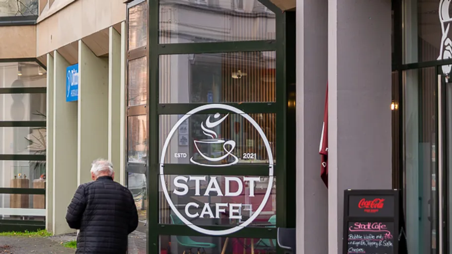 Man walking past a cafe entrance.