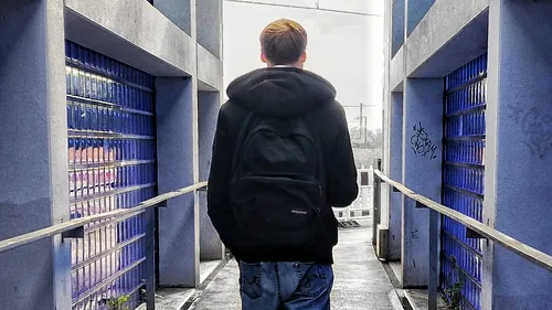 Person walking on walkway between blue walls.