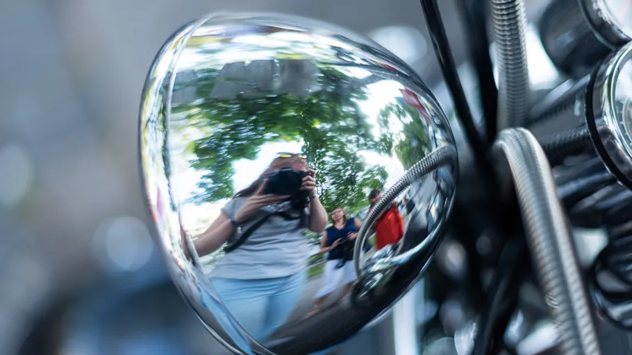 Reflection in motorcycle headlight, people visible.