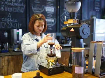 Barista prepares coffee with Chemex in a café.