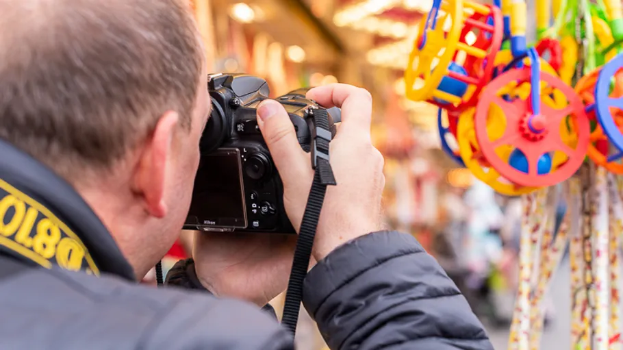 Person photographing colorful toys at a market.