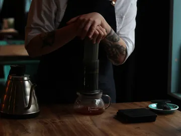 Coffee brewer presses on a coffee maker in a café.