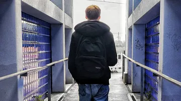 Person with backpack walking on urban walkway.