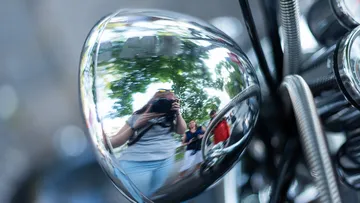 Spiegelung in glänzendem Motorradteil im Freien.