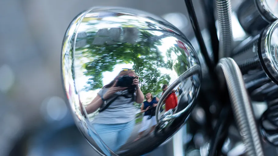 Reflection in a shiny motorbike part outdoors.
