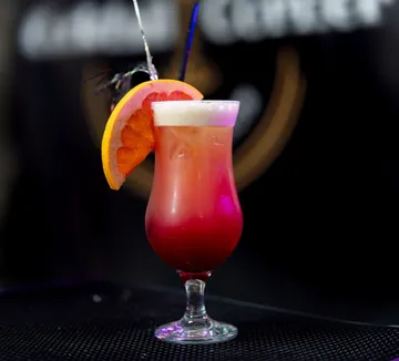 Colorful cocktail with orange slice garnish indoors.
