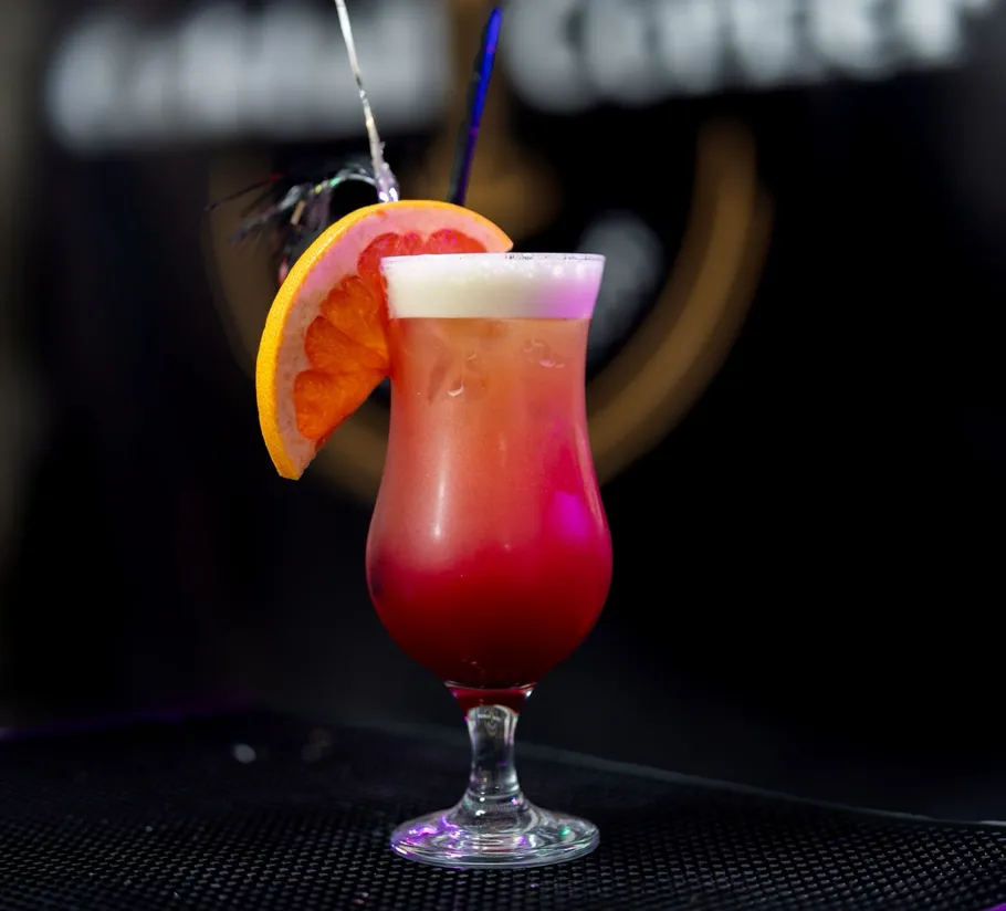 Bunter Cocktail mit Orangenscheibe drinnen garniert.