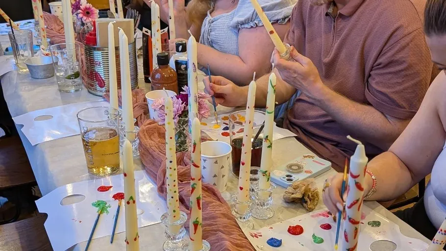 People painting candles at a table.