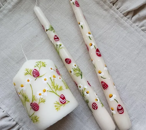 Three decorated candles on linen fabric.