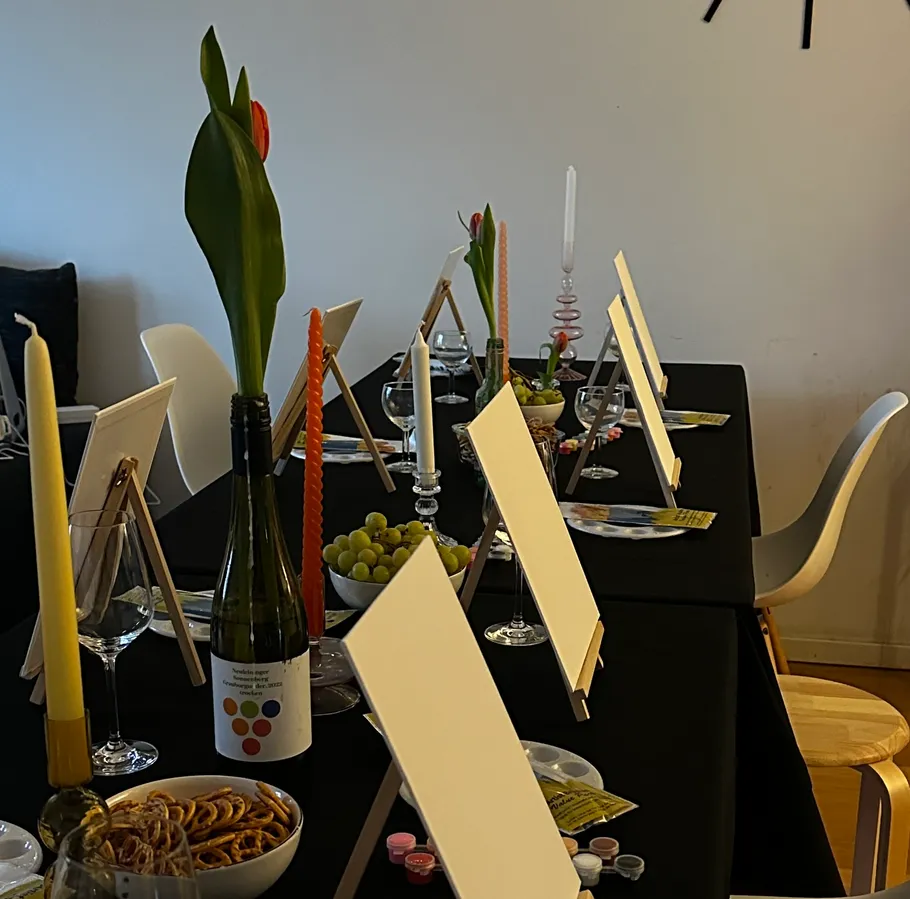 Tisch mit Staffeleien, Kerzen und Essen arrangiert.