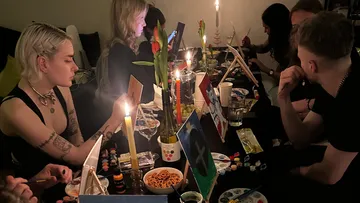 Gruppe von Menschen malt in kerzenbeleuchtetem Raum.