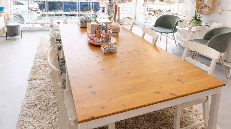 Large wooden table with art supplies in studio.