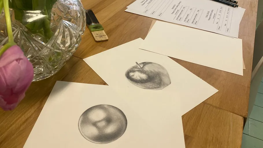 Zeichnungen von Apfel und Kugel auf Tisch.