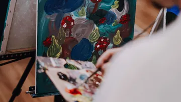 Person malt abstraktes Kunstwerk auf Staffelei.