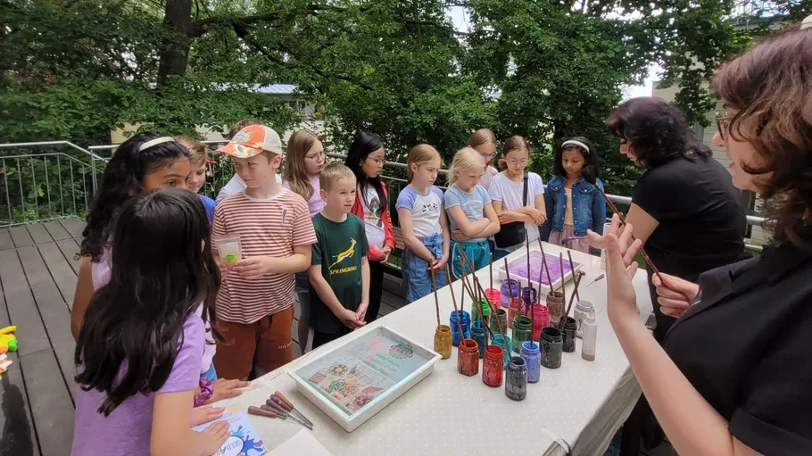 Children gathered around art supplies outdoors.