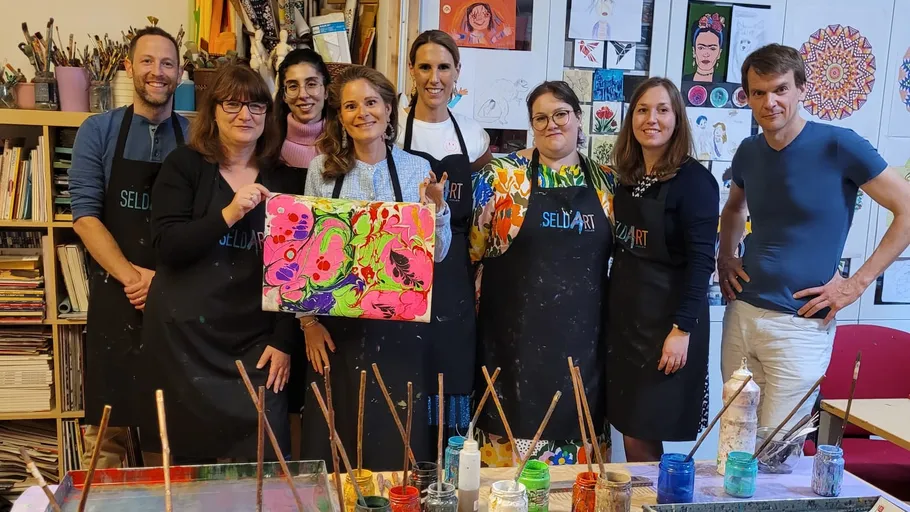 Gruppe hält bunte Kunstwerke im Studio.