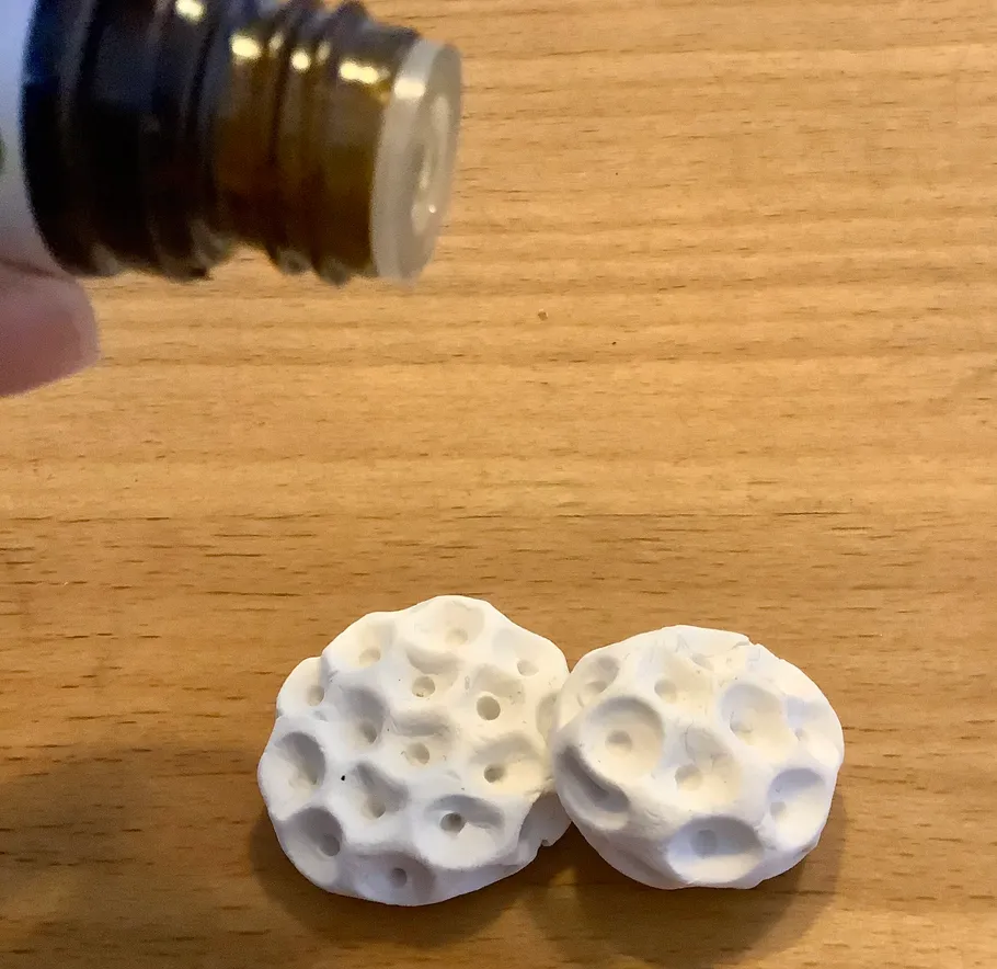 Oil bottle above porous white disks on wood.