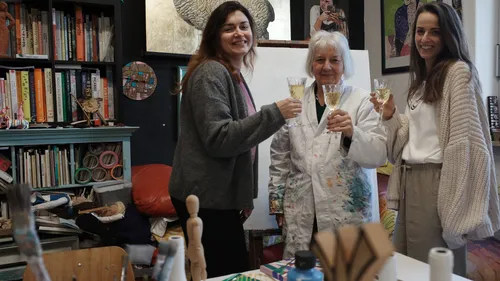 Drei Frauen im Kunststudio stoßen mit Weingläsern an.