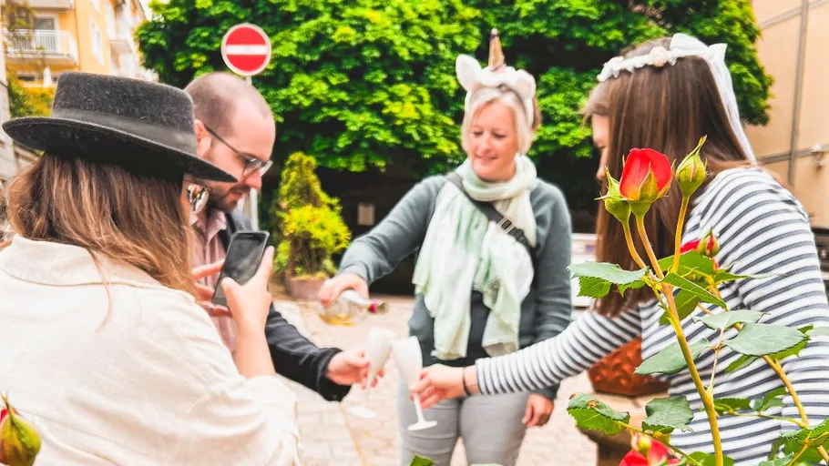 People pouring drinks outdoors, surrounded by roses.