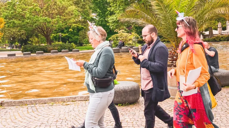 Personen spazieren im Park mit Papieren.