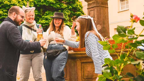 Four people laughing and drinking outdoors.