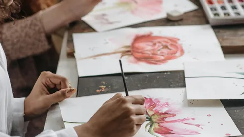 Hände malen Blumen auf Papier.