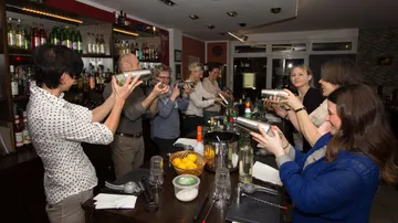 Personen schütteln Cocktailshaker in einer Bar.