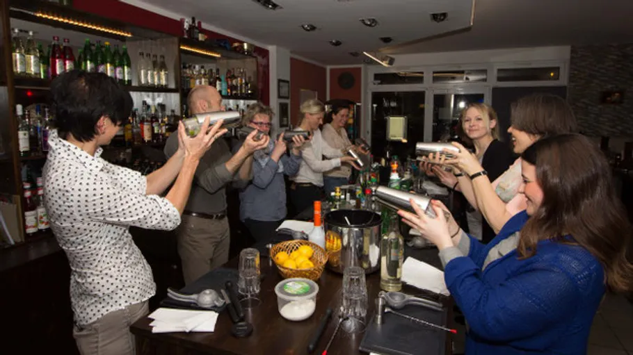 People shaking cocktail shakers in a bar.