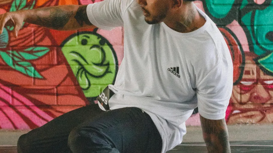 Man breakdancing with colorful graffiti background.