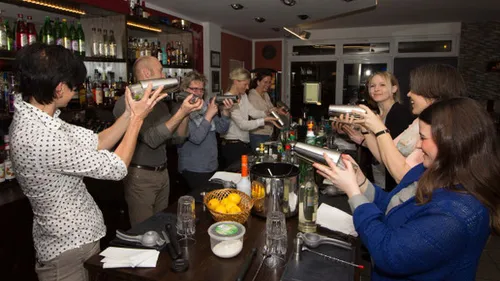 People shaking cocktail shakers in a bar.