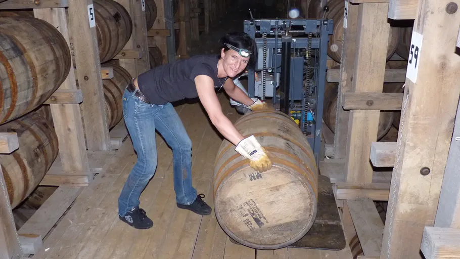 Person rolling a barrel in a warehouse.