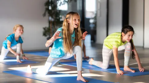 Kinder üben Yoga-Posen drinnen.