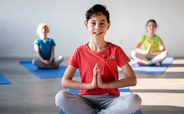 Kinder üben Yoga auf Matten drinnen.