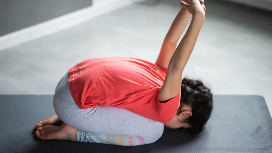 Person macht Yoga-Kindhaltung auf Matte.