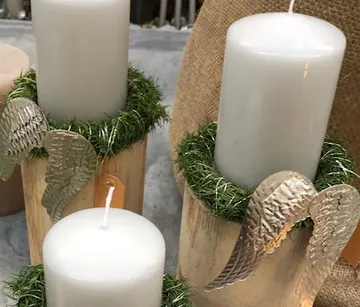 Candles are decorated in wooden pods with angel wings.