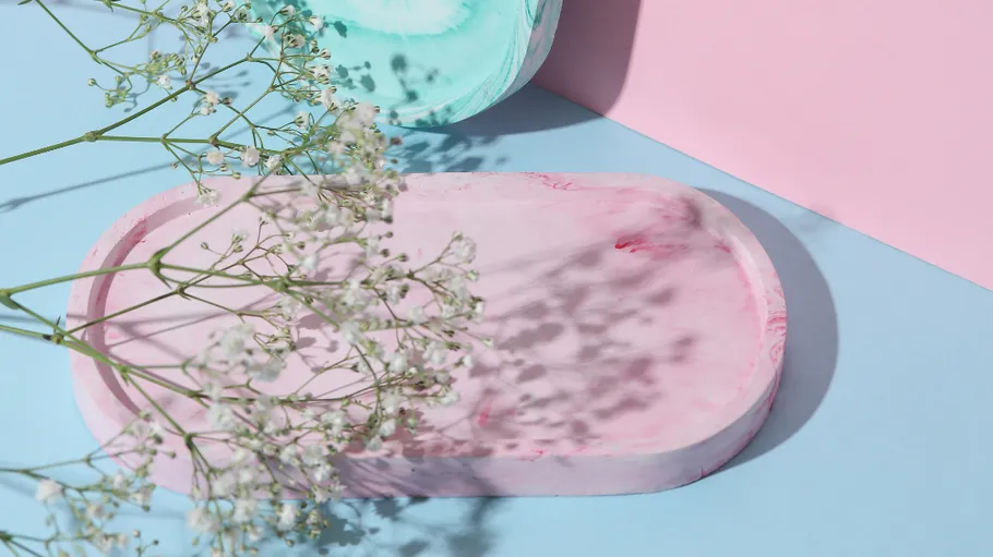 Rosa Tablett mit Blumen auf pastelliger Oberfläche.