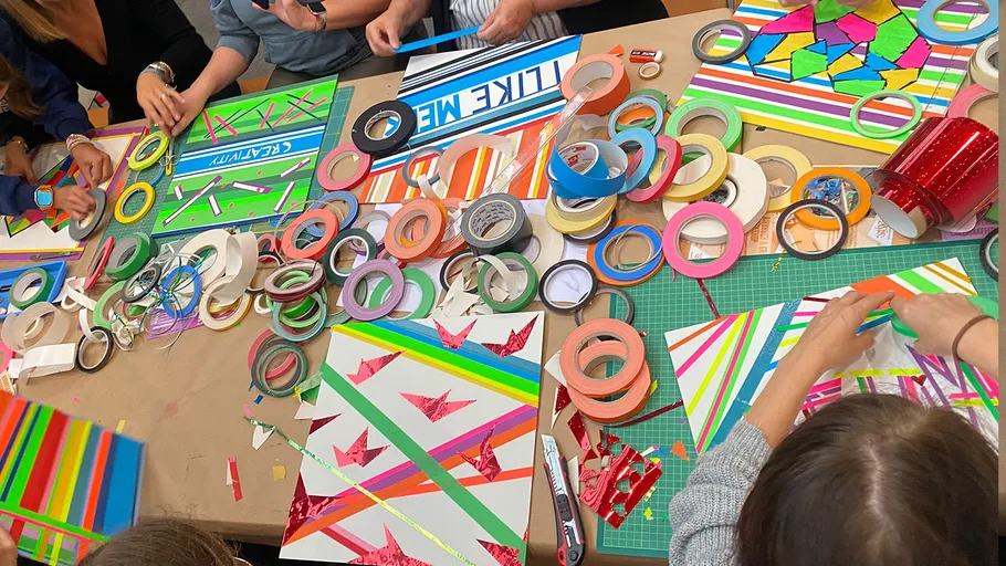 Menschen basteln mit Klebebändern am Tisch.