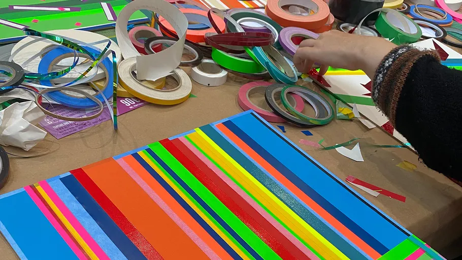 Colorful tape strips on table, hand arranging.