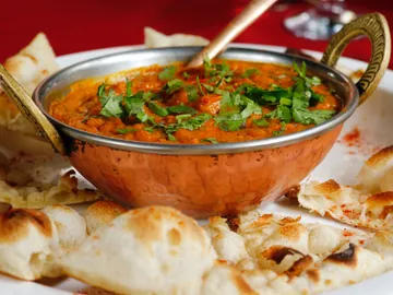 Edelstahl-Schale mit würzigem Curry und knusprigem Brot.