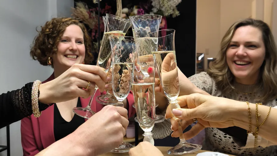 People clinking champagne glasses, smiling indoors.