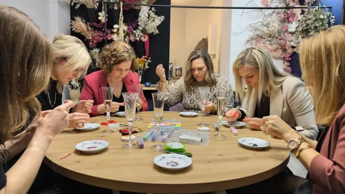 Women crafting bracelets at a table.