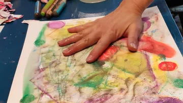 Hand drückt buntes Bild auf Schreibtisch.