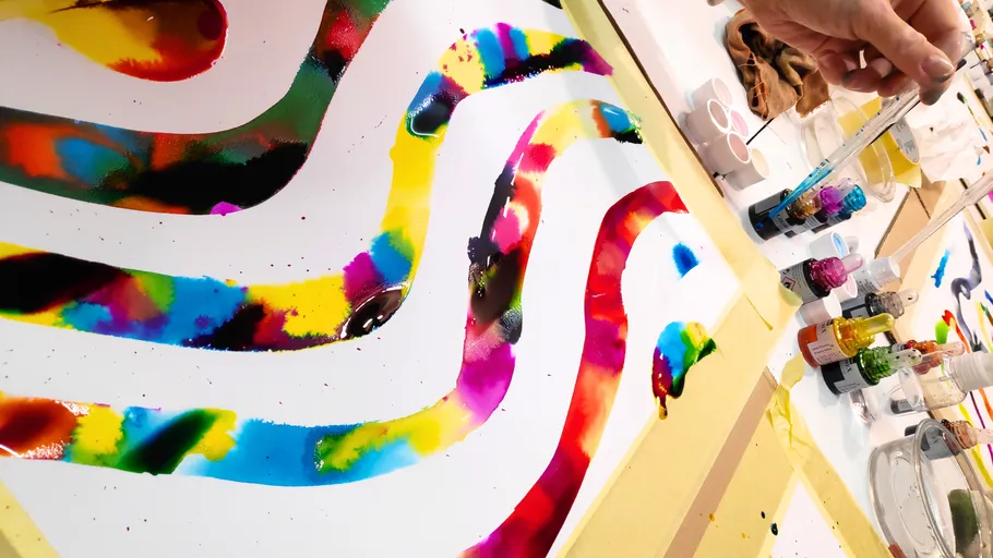 Colorful paint swirls on paper, hand using pipette.