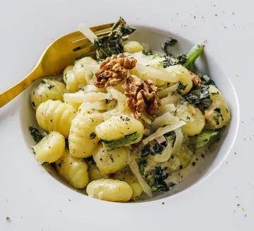Pasta mit Spinat und Walnüssen in weißem Teller.