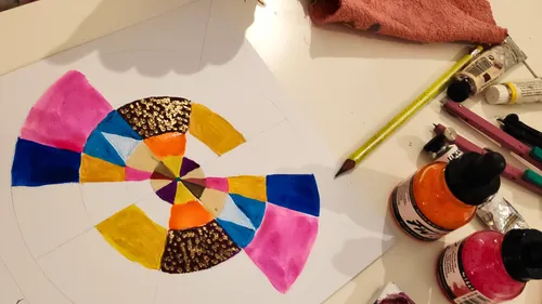 Colorful geometric painting with paint bottles nearby.