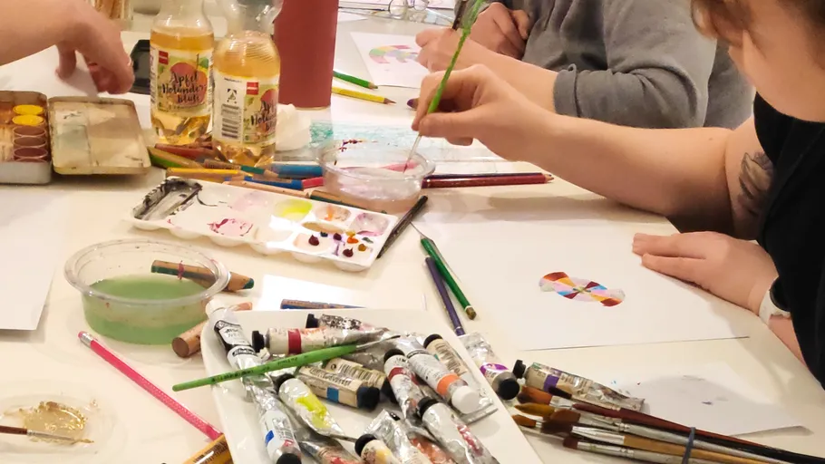 People painting at a table with supplies.