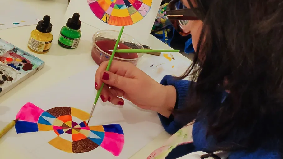 Person painting colorful geometric design on paper.