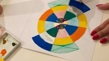 Colorful geometric mandala being painted by hand.