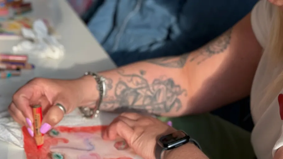 Tätowierter Arm malt mit Pastell auf Tisch.