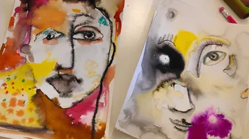 Two abstract face paintings on a table.